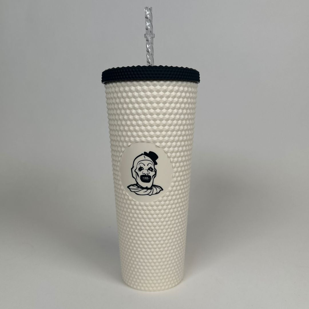 a white textured tumbler with black lid with a clown engraved in the middle