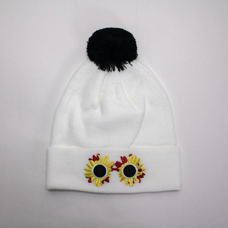 White beanie with black pom-pom and sunflower horror design on a light gray background