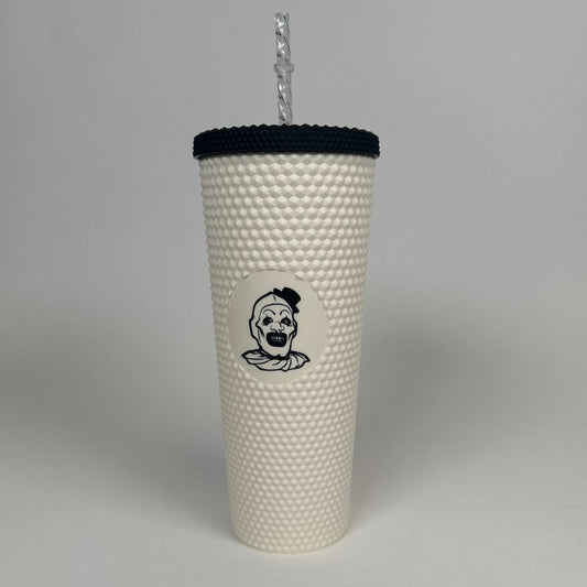 a white textured tumbler with black lid with a clown engraved in the middle