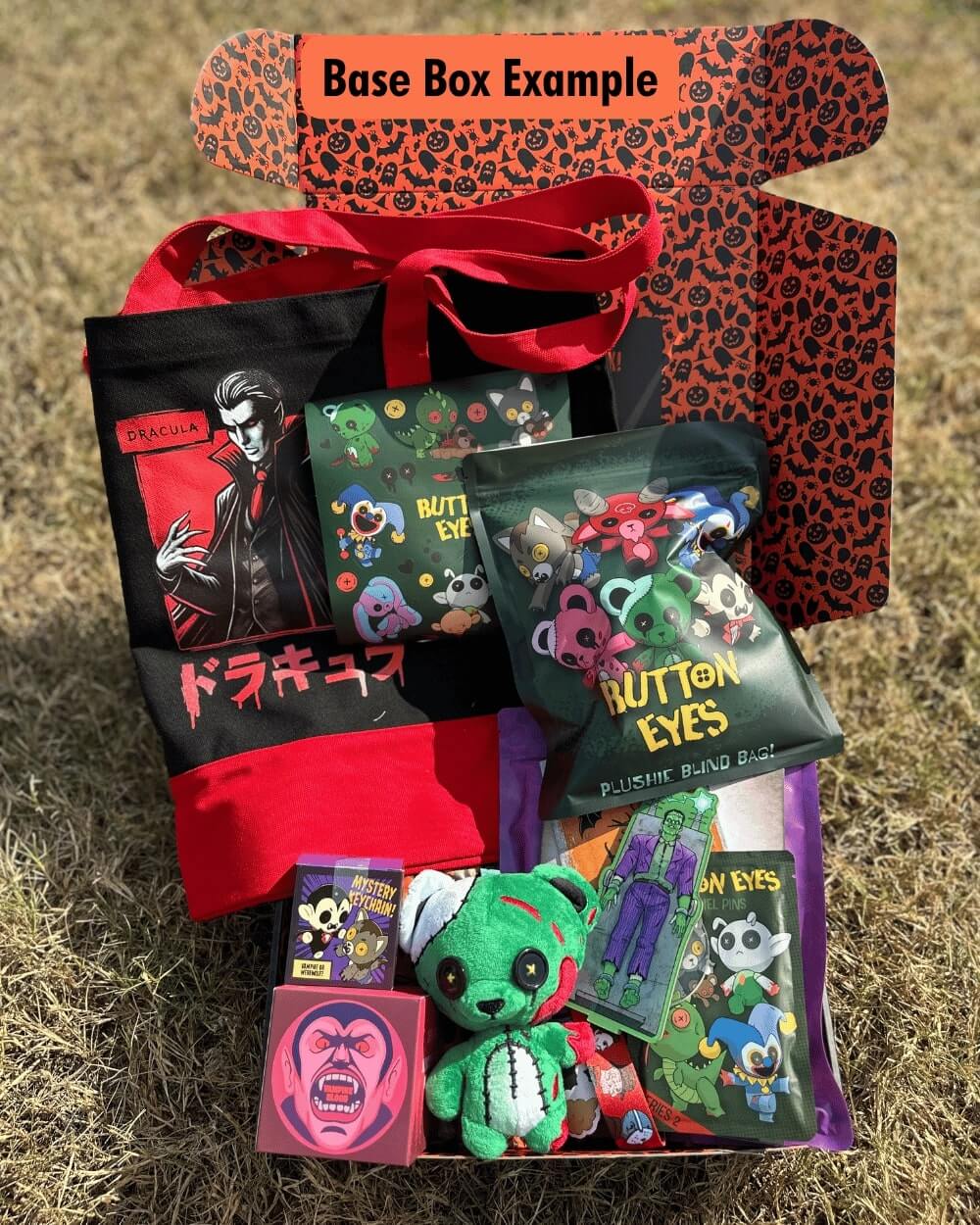 Halloween mystery box with various collectible items including plush toys, cards, and bags on a grassy background.