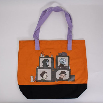 Orange tote bag with Horror slasher design and black bottom section and purple handles on a white background