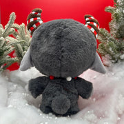 red background with black goat "Krampus" plushie standing on snow
