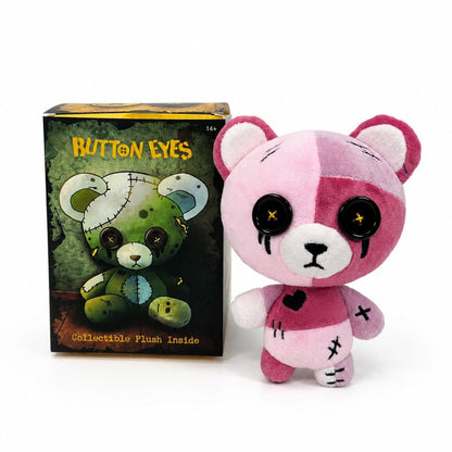 A pink and white split-color plush Buttoneyes teddy bear with black button eyes and stitched details, standing next to its dark green illustrated product box labeled 'BUTTONEYES' on a white background.