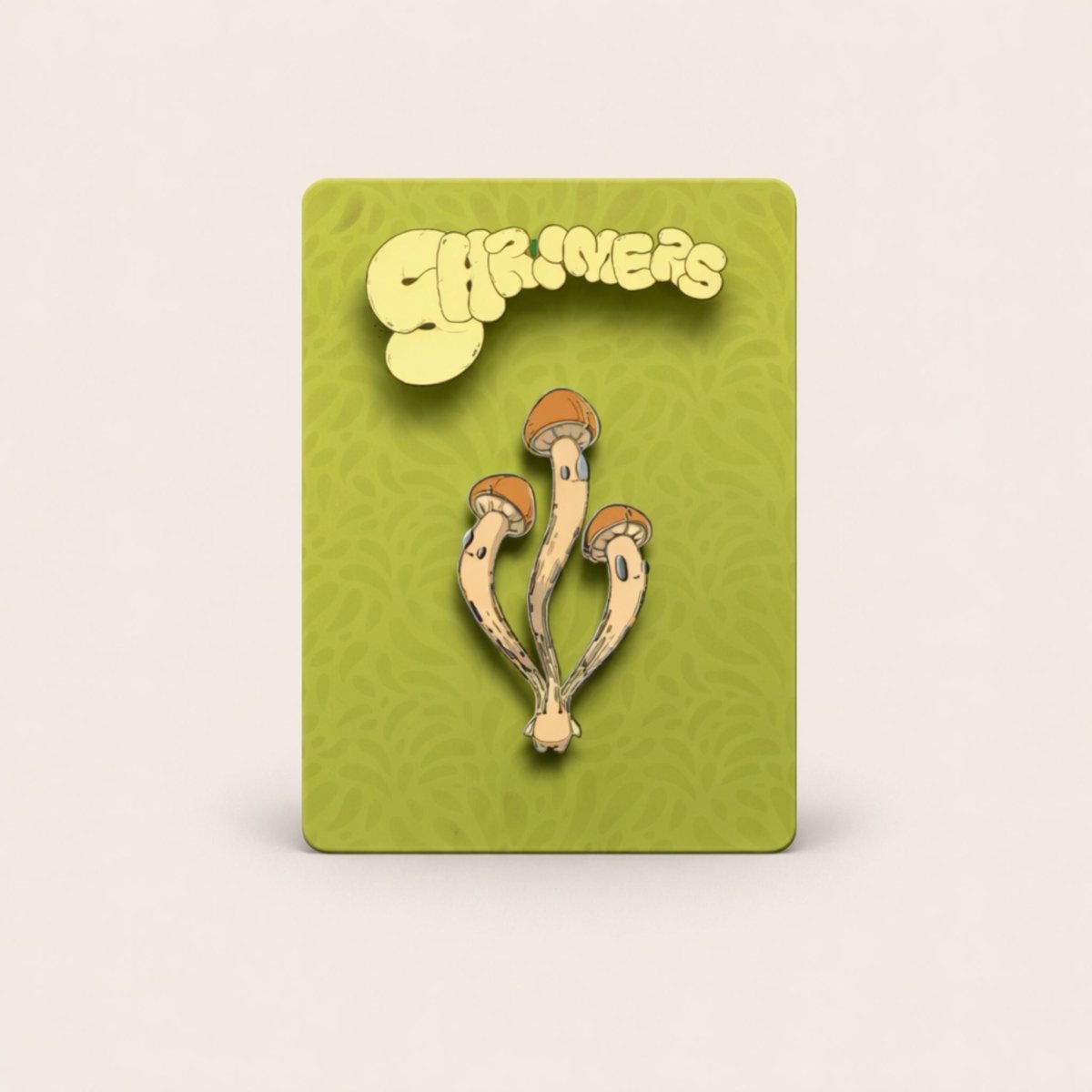 Enamel pin of mushrooms on a green card with 'Shroomers' branding.