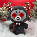 red background with black goat "Krampus" plushie standing on snow