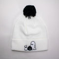 White beanie with black pom-pom and Halloween-themed ghost & ghost dog embroidery on a light gray background